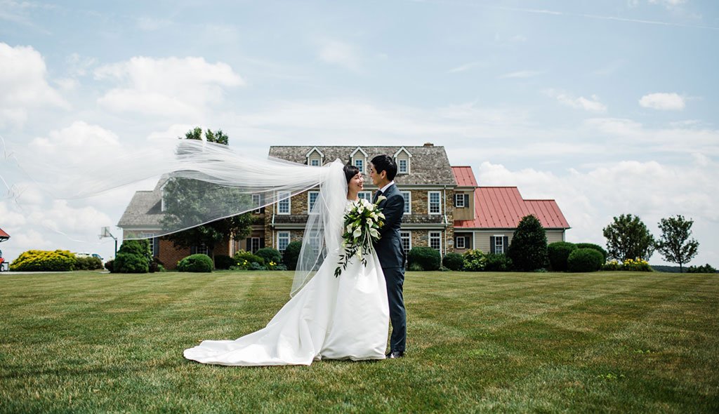 Bride and Groom Standing in front of The Inn at Wyndridge Farm